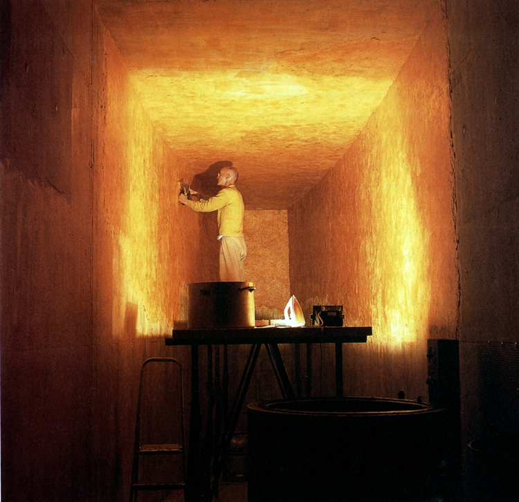 Photo of Wolfgang Laib using a warm iron to smooth the walls of the wax chamber on his own property in southern Germany. Courtesy of the artist