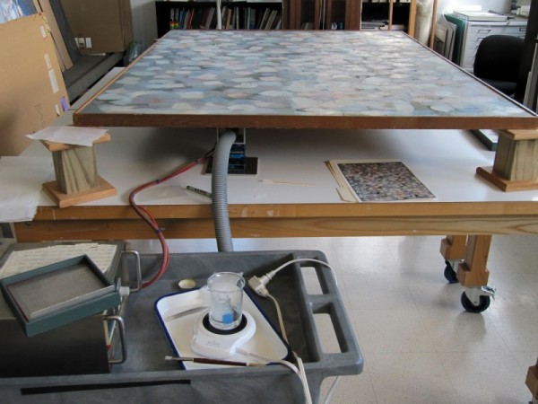 For consolidation, the 66 x 48-inch painting was placed flat and elevated on blocks.  A flat suction platen was placed underneath, against the back of the canvas (The grey hose that attaches the adjustable platen to a vacuum can be seen in the picture above).  