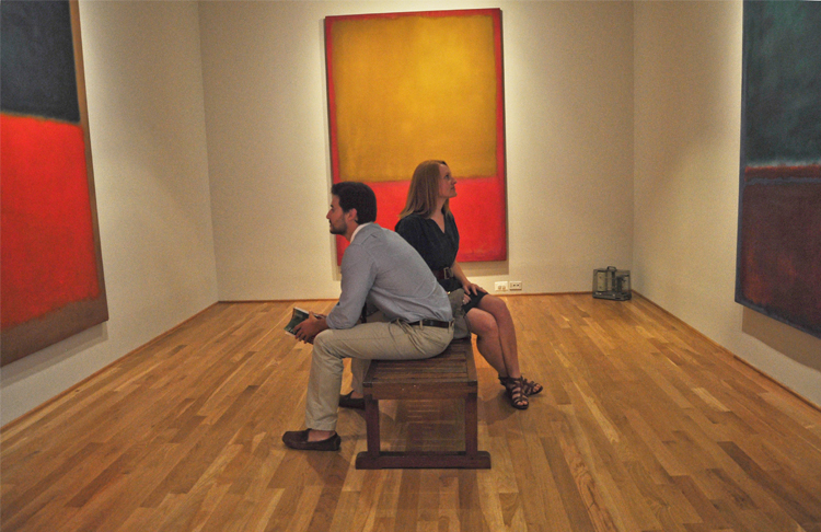 Two visitors sit on a bench in the middle of the Rothko Room at the Phillips