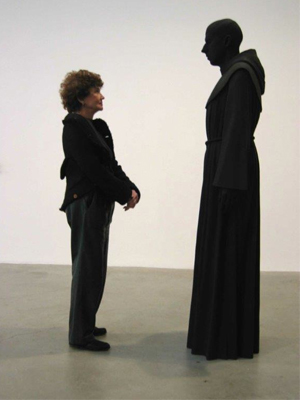 Anita Reiner standing in front a human figure cloaked in black.