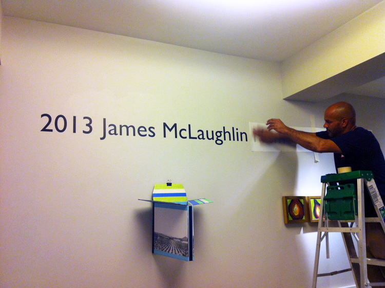 A Phillips preparator installs the title wall of the staff show.