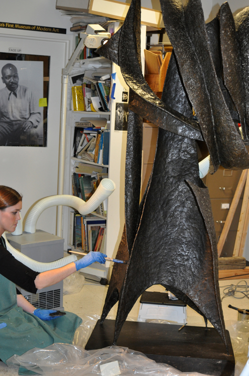 After cleaning, applying wax to the surface of "Ancestor" (1958), by Seymour Lipton.